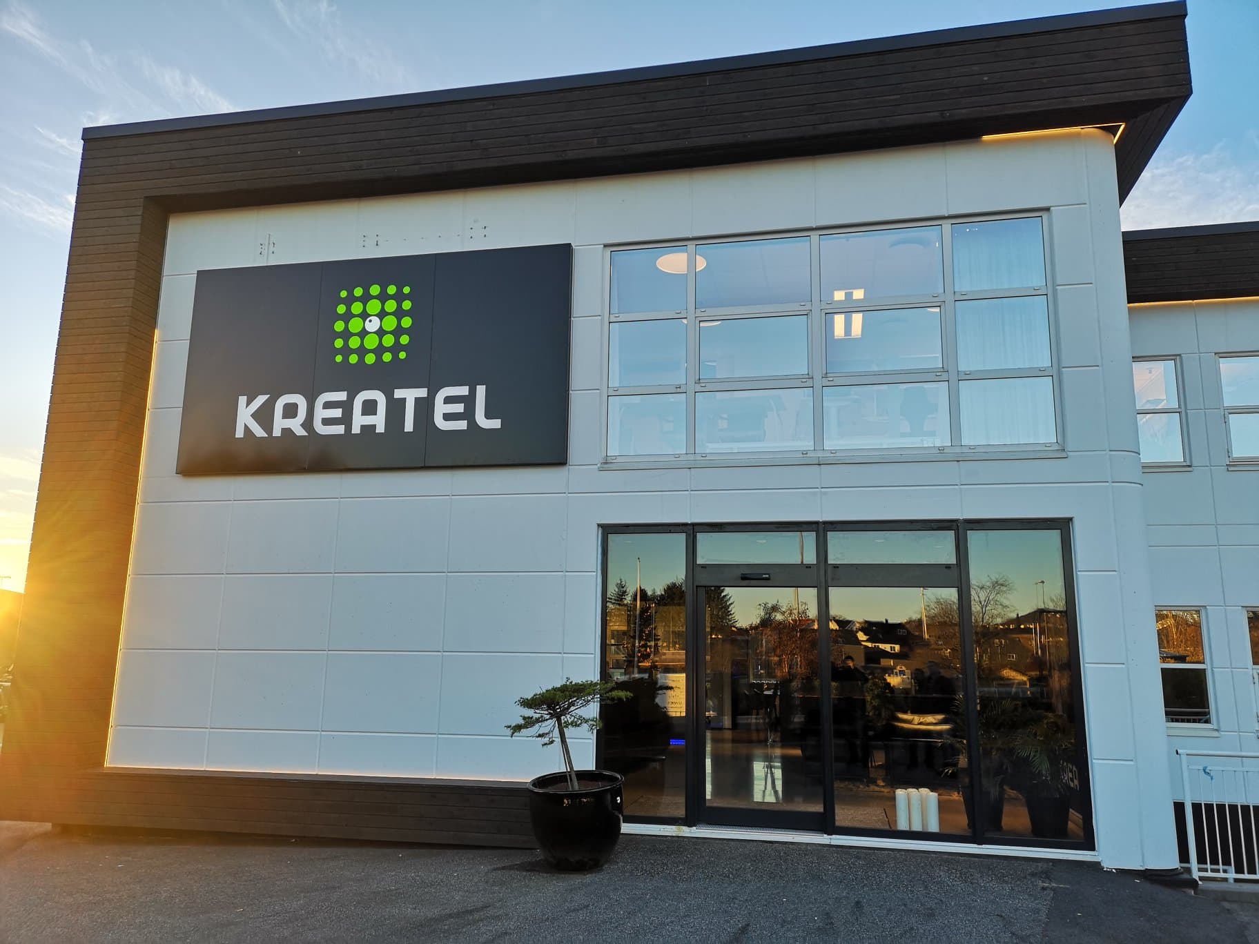 Fasadeskilt for Kreatel med firmalogo og bokstaver på hvit bygningsfasade i Rogaland