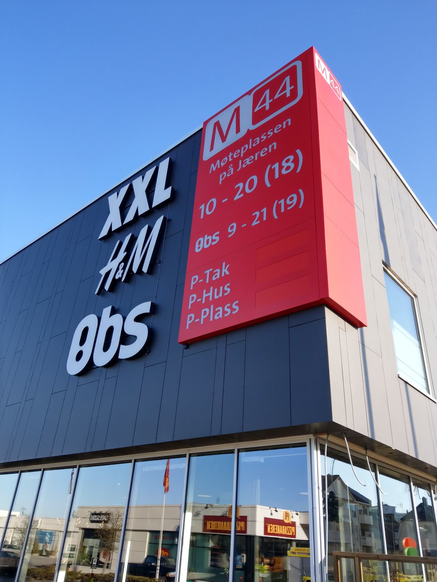 Fasaden på M44 Kjøpesenter med lysskilt for XXL, H&M og Obs